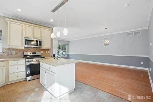 kitchen featuring appliances with stainless steel finishes, cream cabinets, light countertops, tasteful backsplash, and crown molding