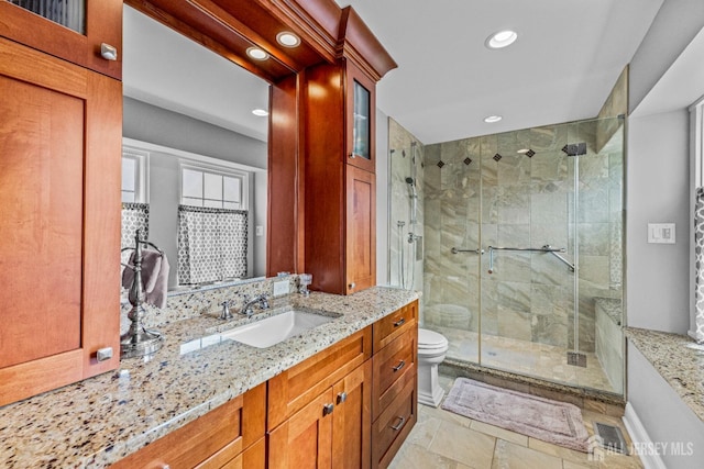 bathroom with stone tile floors, toilet, vanity, a shower stall, and recessed lighting