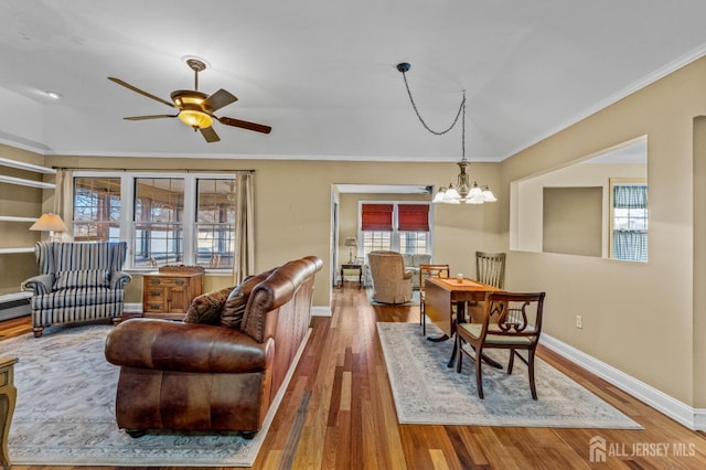 living room with baseboards, ceiling fan with notable chandelier, wood finished floors, and crown molding