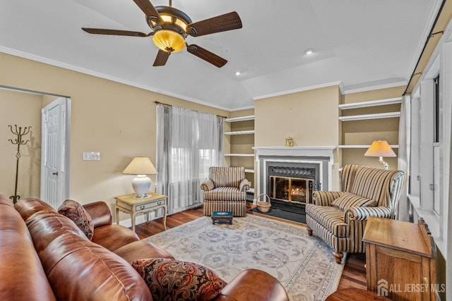 living room with a fireplace with flush hearth, a ceiling fan, ornamental molding, and wood finished floors