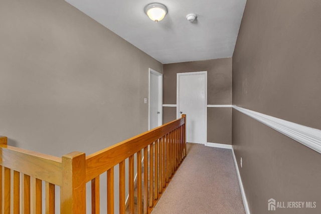 corridor with carpet floors, baseboards, and an upstairs landing