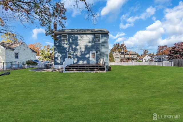 rear view of house featuring a yard and a fenced backyard