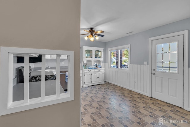 kitchen with a wainscoted wall, visible vents, white cabinets, light countertops, and brick patterned floor