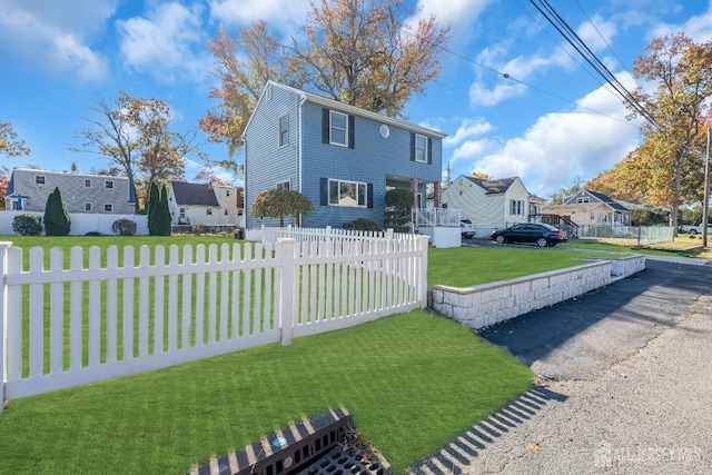 view of front facade featuring fence private yard, a residential view, and a front yard