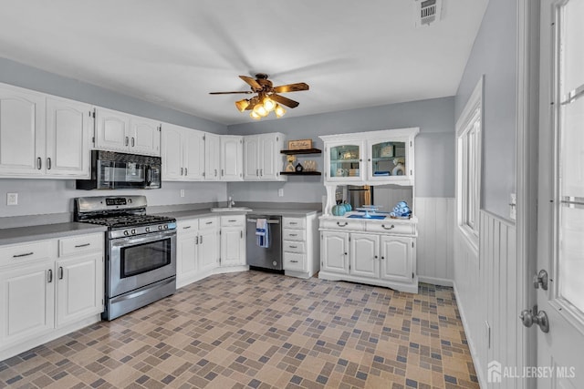 kitchen featuring open shelves, gas stove, wainscoting, black microwave, and dishwashing machine