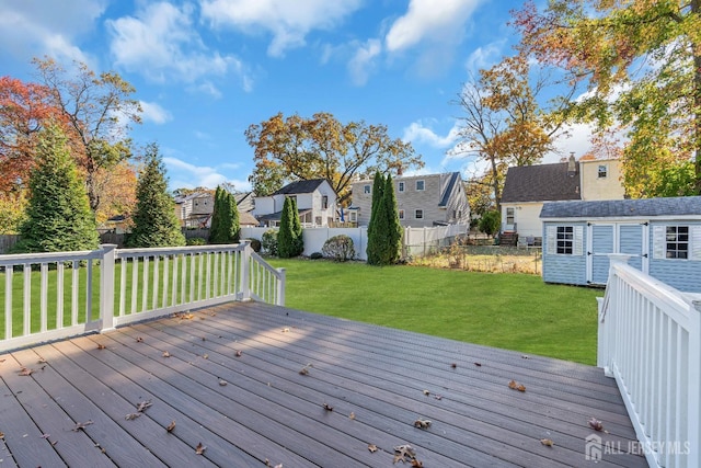 wooden deck featuring a yard, a fenced backyard, a residential view, and an outdoor structure