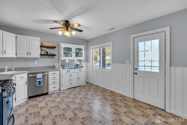 kitchen featuring a wainscoted wall, open shelves, visible vents, appliances with stainless steel finishes, and a sink