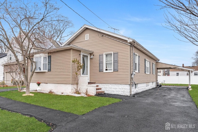 bungalow-style house featuring driveway, a front lawn, and fence