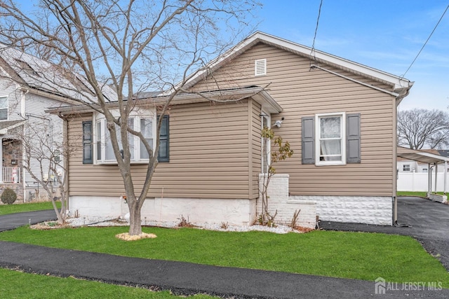 view of property exterior featuring a carport, a yard, and driveway