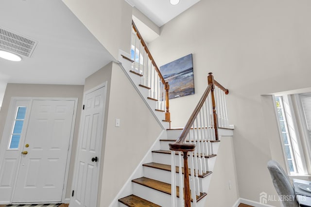 stairway featuring visible vents, plenty of natural light, and baseboards