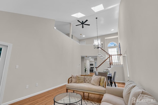 living area with baseboards, a skylight, stairs, and light wood finished floors