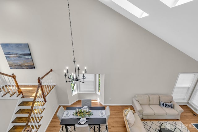 living room with high vaulted ceiling, an inviting chandelier, light wood-style flooring, and stairs