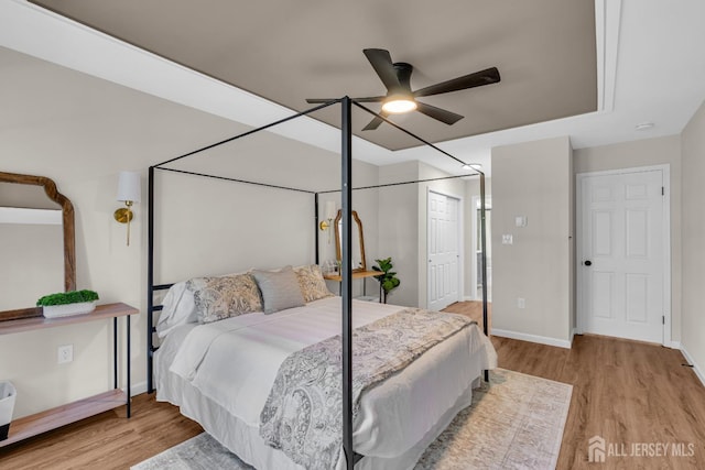 bedroom with a closet, a ceiling fan, baseboards, and wood finished floors