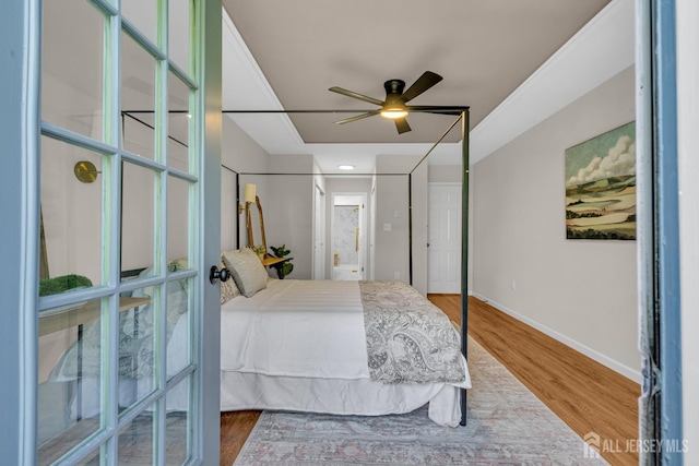 bedroom with connected bathroom, ceiling fan, baseboards, and wood finished floors