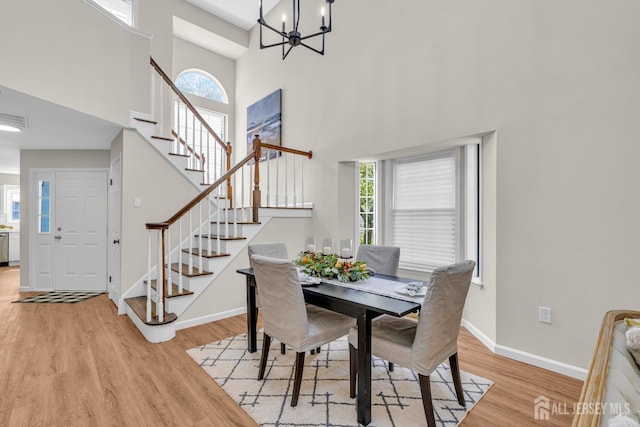 dining space featuring an inviting chandelier, baseboards, stairs, and light wood-style floors