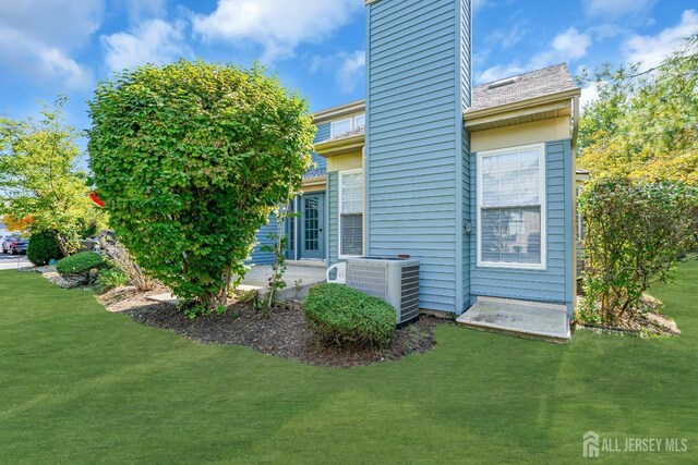 back of property with a patio area, central AC unit, a chimney, and a lawn