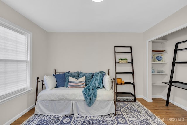 bedroom featuring baseboards, multiple windows, and wood finished floors