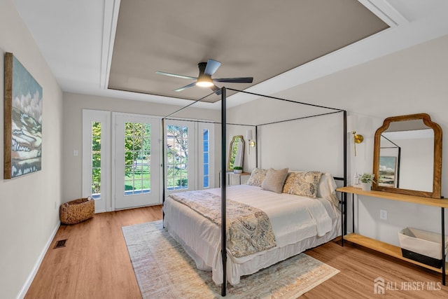 bedroom featuring wood finished floors, visible vents, baseboards, ceiling fan, and access to outside