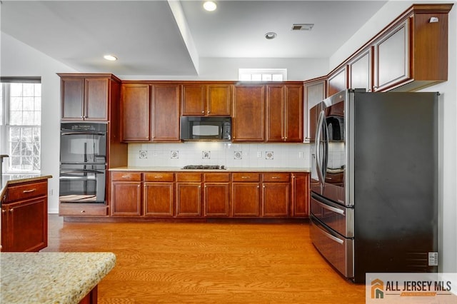 kitchen with recessed lighting, visible vents, backsplash, light wood-type flooring, and black appliances