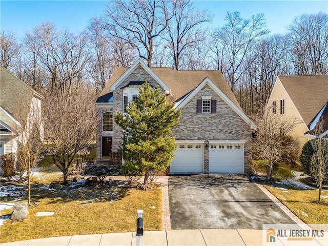 view of front facade with driveway, a shingled roof, an attached garage, a front yard, and brick siding