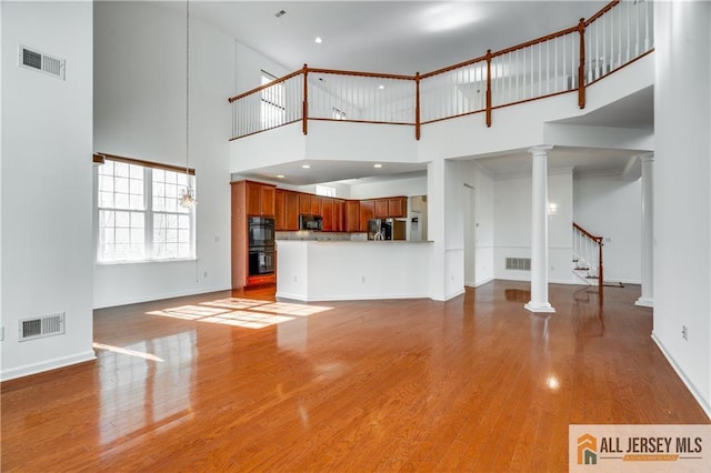 unfurnished living room featuring stairs, baseboards, visible vents, and light wood finished floors