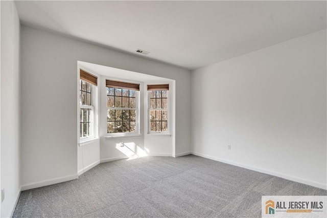 unfurnished room featuring carpet flooring, visible vents, and baseboards