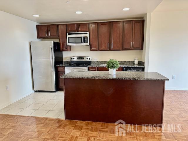110 Somerset St Unit 2101, New Brunswick, NJ 08901 - kitchen featuring stainless steel appliances, dark brown cabinets, dark stone counters, a kitchen island, and recessed lighting
