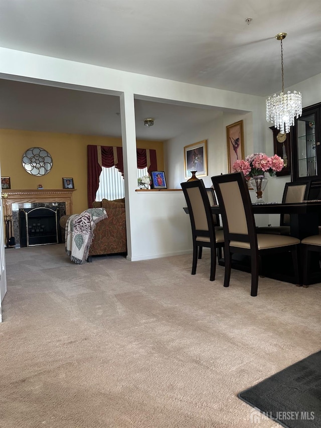 dining room with a chandelier, baseboards, carpet, and a premium fireplace