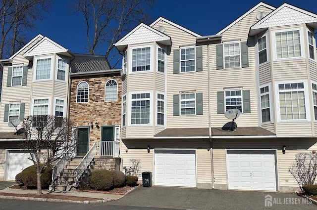 townhome / multi-family property with stone siding, a garage, and driveway