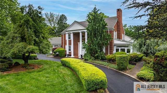 57 Patton Dr, East Brunswick, NJ 08816 - neoclassical home featuring a front yard, brick siding, and a chimney
