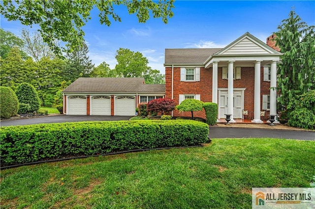 57 Patton Dr, East Brunswick, NJ 08816 - neoclassical / greek revival house with a garage, asphalt driveway, a front lawn, a chimney, and brick siding