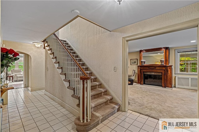 57 Patton Dr, East Brunswick, NJ 08816 - staircase with tile patterned floors, healthy amount of natural light, a glass covered fireplace, carpet, and wallpapered walls