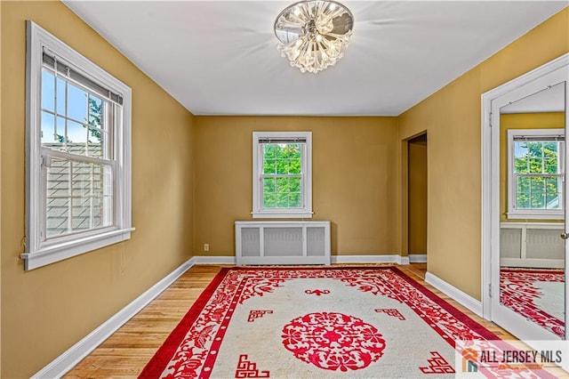 57 Patton Dr, East Brunswick, NJ 08816 - empty room with radiator, plenty of natural light, wood finished floors, and a chandelier