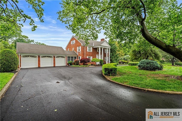 57 Patton Dr, East Brunswick, NJ 08816 - neoclassical home with a garage, asphalt driveway, a chimney, and a front yard