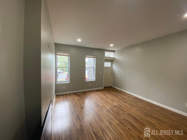 empty room with dark hardwood / wood-style flooring and a wealth of natural light