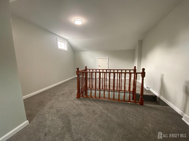 additional living space with dark carpet and vaulted ceiling