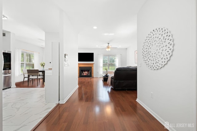 hall featuring baseboards, recessed lighting, and wood finished floors