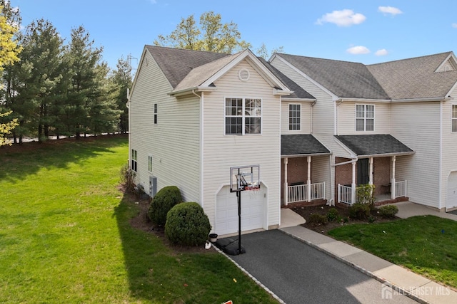 view of front of property with a porch, aphalt driveway, a front lawn, and a garage