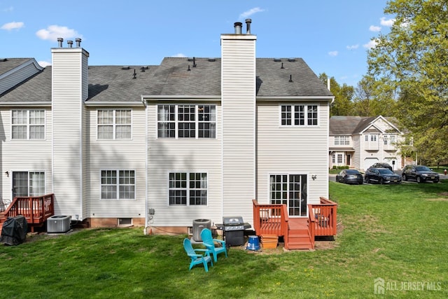 rear view of property featuring a chimney, roof with shingles, a deck, central AC unit, and a yard
