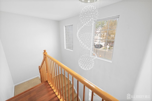 stairway featuring baseboards and a chandelier