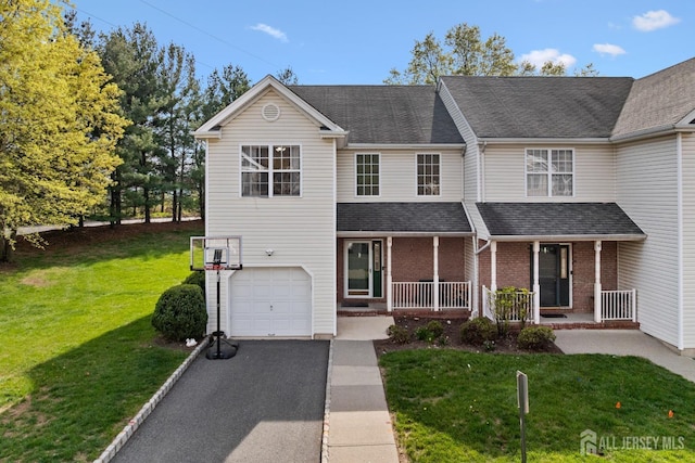 traditional home featuring covered porch, a front yard, aphalt driveway, an attached garage, and a shingled roof