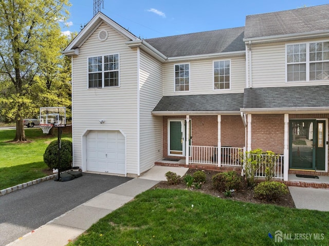 traditional-style house with covered porch, driveway, a front lawn, and a garage