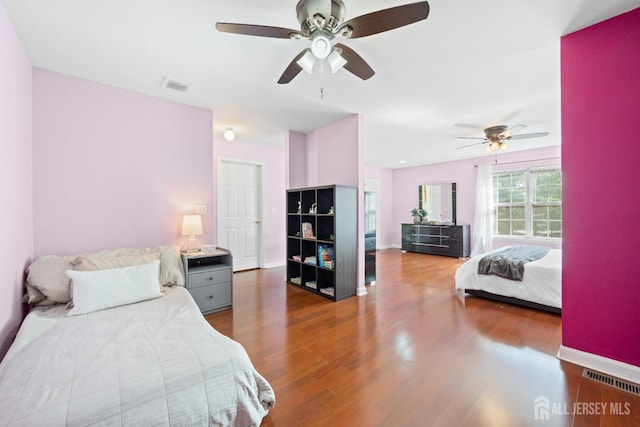 bedroom with a ceiling fan, baseboards, visible vents, and wood finished floors