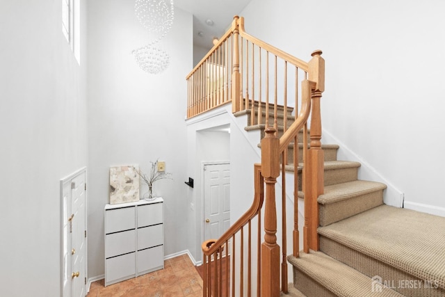 staircase with baseboards and a towering ceiling