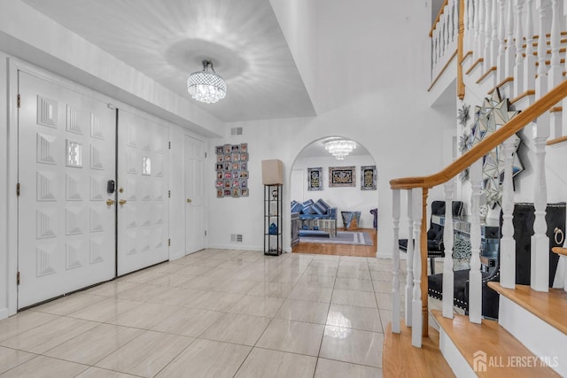 foyer featuring tile patterned flooring, visible vents, stairs, an inviting chandelier, and arched walkways