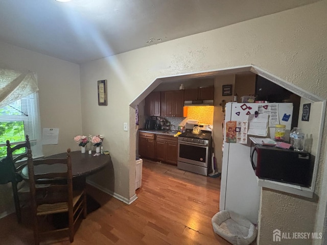 166 Fulton St, New Brunswick, NJ 08901 - kitchen with stainless steel range with gas stovetop, light wood-type flooring, black microwave, a textured wall, and freestanding refrigerator