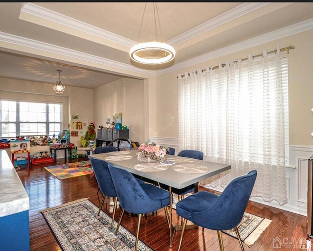 dining room with dark hardwood / wood-style flooring, crown molding, a raised ceiling, and a chandelier