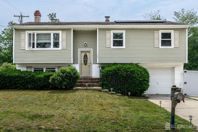 701 Beach Ave, Beachwood, NJ 08722 - split foyer home with a chimney, a front yard, solar panels, an attached garage, and concrete driveway