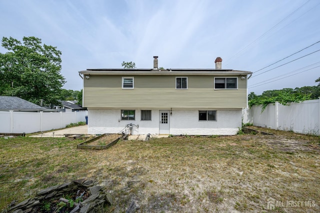 701 Beach Ave, Beachwood, NJ 08722 - back of property with a fenced backyard, a vegetable garden, roof mounted solar panels, and a chimney