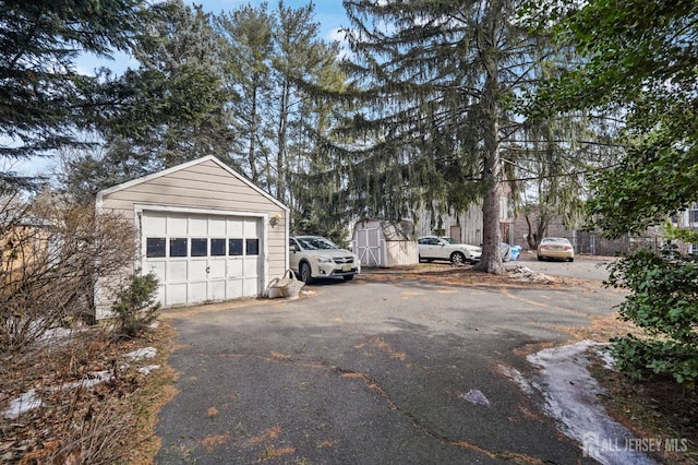 detached garage with aphalt driveway and fence